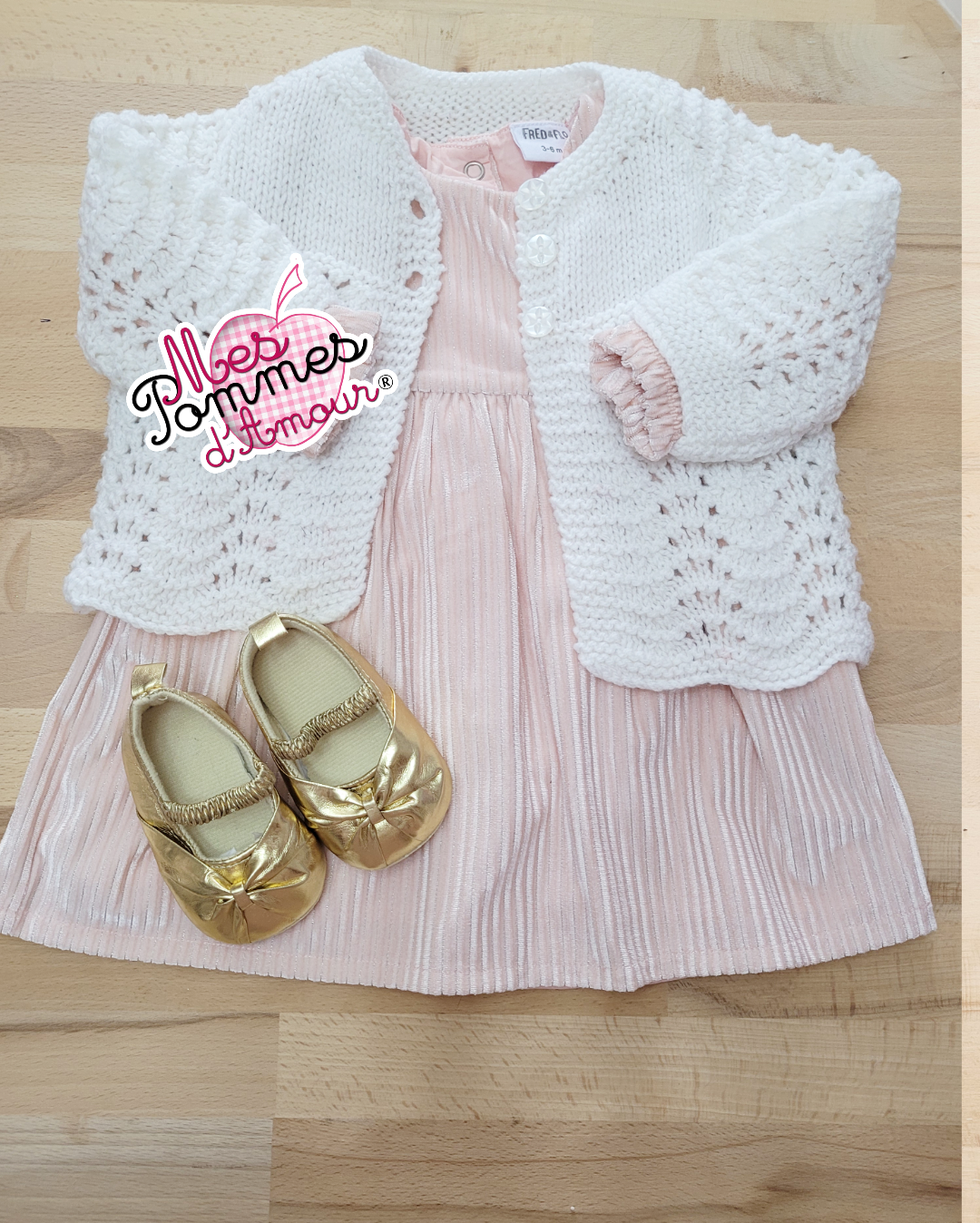 Ensemble de vêtements layette avec une robe et un gilet blanc et des petites chaussures dorées pour bébé afin de mettre dans le ballon bleu